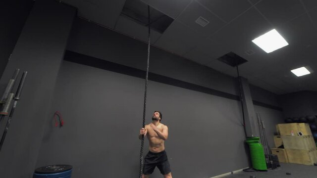 Athlete climbing rope in gym