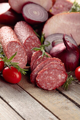 Food tray with delicious salami, ham, fresh sausages, tomato, and rosemary.