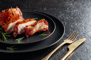 Grilled pork ribs on a black plate.
