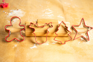 Preparing for Christmas. Red gingerbread shapes are put together in a row, next to the dough roll.