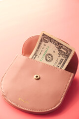 Us dollar cash in a small wallet on pink background 