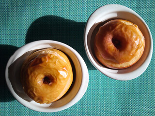 Two freshly baked apples in white bowls on blue background. Healthy snack concept. Top view. Hard light.