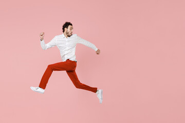 Fototapeta na wymiar Full length side view of shocked worried young bearded man 20s wearing basic casual white shirt jumping like running looking aside isolated on pastel pink color wall background studio portrait.