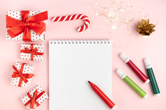 Notepad wish list on a pink table with felt-tip pens on a Christmas background with mock up. Concept of christmas, new year, plans and making wishes