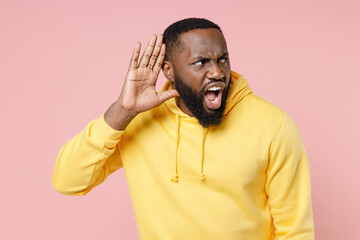 Shocked curious young african american man 20s in casual yellow streetwear hoodie try to hear you...