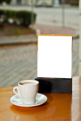 Tablet with white place for text on a wooden board. Coffee near the stand on the table. Mockup for design. Copy space for advertising.