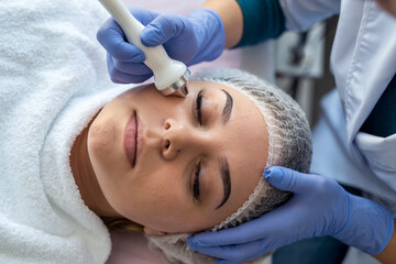 cosmetologist using ultrasound cavitation machine doing procedure lifting therapy massage