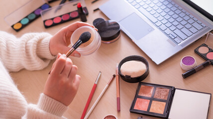 A faceless woman watches online training from a professional makeup artist on a laptop. Distance learning