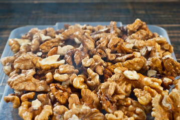 Walnut texture with steam close up. Many halves of peeled nuts on an old wooden board. Food in blue smoke on a background of shabby brown board. Contrasting dramatic light.