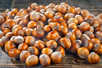 Hazelnuts on a pile close up. Texture of nuts on an old wooden board. Lots of nuts on a brown shabby table.