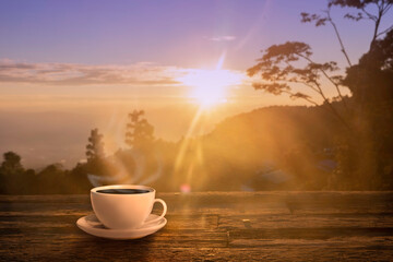 Close up coffee cup on wood table at sunset or sunrise background.