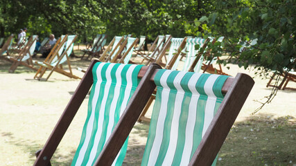 Pairs of empty green stripped deck chairs St James's Park, London, UK..