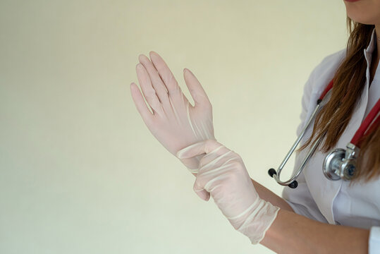 Female doctor puts on protective surgical gloves before hard work day in clinic