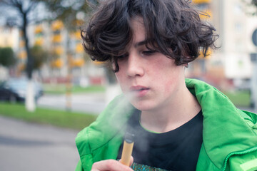 a young guy addicted to nicotine smokes an electronic cigarette. the dependence on cigarettes