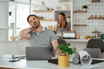 Young businessman having backache. Handsome man working at home.