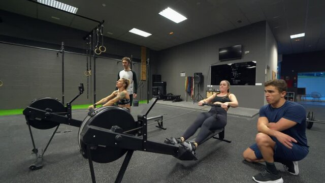 Athletes exercising on rowing machines at gym