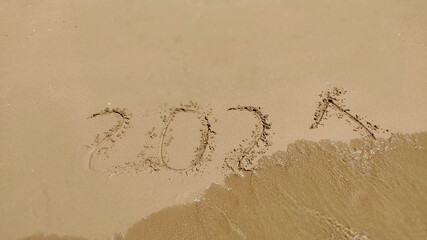 Numbers 2021 year written on the sand in sea beach