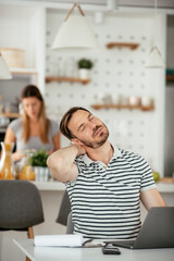 Young businessman having backache. Handsome man working at home.