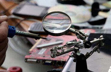 Manual worker human hand holding soldering iron tool repairing computer electronics circuit board