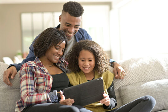 African-american family of three using digital tablet - Powered by Adobe