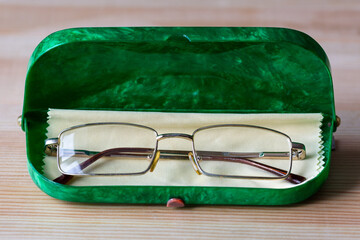 Glasses for eyes in a green case and a cleaning cloth.