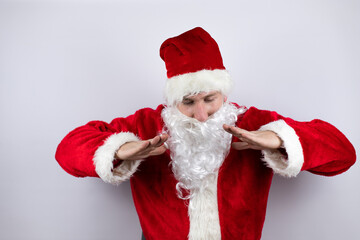 Fototapeta na wymiar Man dressed as Santa Claus standing over isolated white background shouting and screaming loud down with hands on mouth