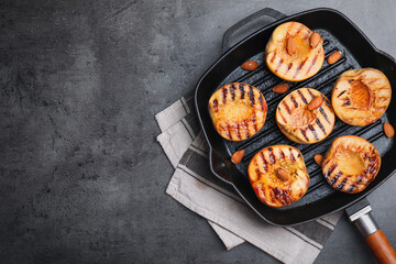 Delicious grilled peaches with almonds on grey table, top view. Space for text