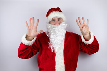 Fototapeta na wymiar Man dressed as Santa Claus standing over isolated white background showing and pointing up with fingers number nine while smiling confident and happy