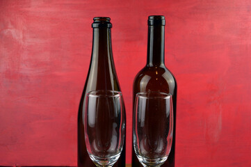 
empty glasses and bottles of wine stand on wooden background