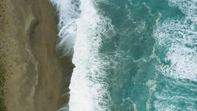 Vista aera di un'onda che si infrange sulla spiaggia sabbiosa.