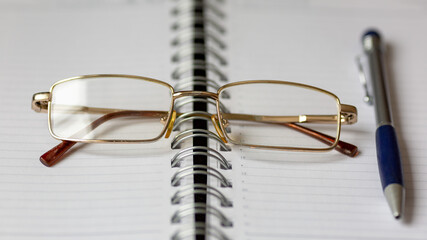 Glasses and pen on an open notebook.