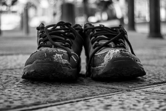 Old pair of worn abandoned boots on the tamarc road. Photography in black and white