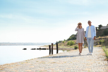 Happy couple walking along waterfront on summer day