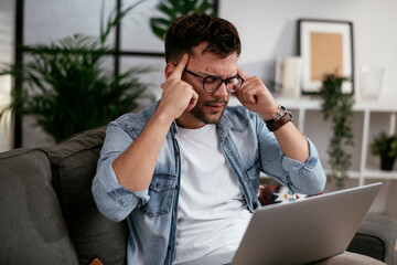 Young angry man having video call. Man sitting in the living room and using the laptop..