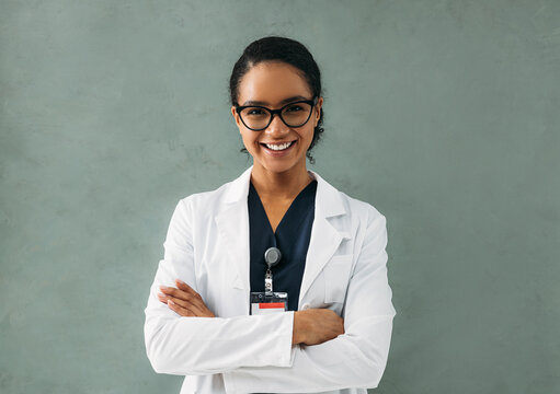 Portrait Of Smiling Female Doctor With Crossed Arms. Young Medical Specialist Wearing Eyeglasses And White Jacket.