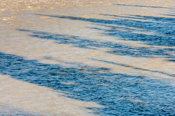 shadows of trees on the surface of a silt loaden river
