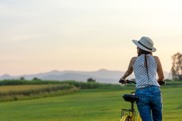 Lifestyle woman with bicycling at the garden meadow in sunset near mountain background.  Lifestyle  Concept