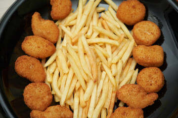 Fried chicken nuggets with french fries, top view