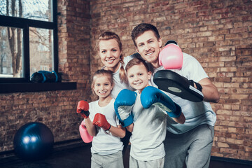 Dad and mom stand in gym in boxing gloves. 