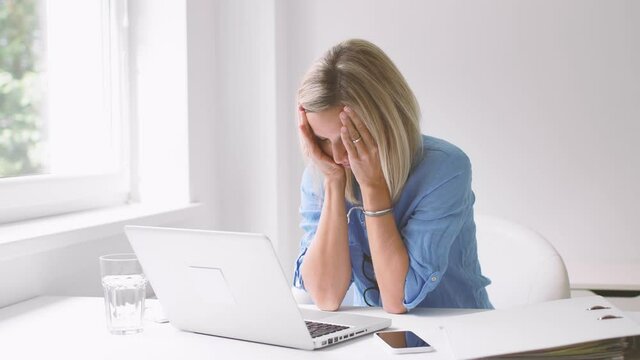Overworked businesswoman falling asleep in front of laptop