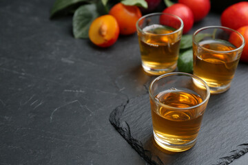 Delicious plum liquor on black table. Homemade strong alcoholic beverage