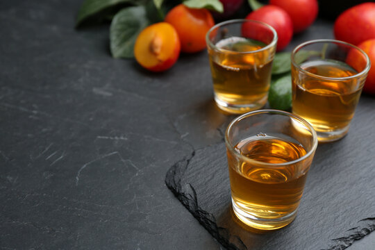 Delicious plum liquor on black table. Homemade strong alcoholic beverage
