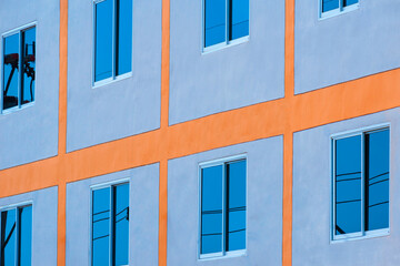 Low angle and side view of blue sky reflection on glass windows surface of modern building wall