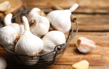 Fresh organic garlic in basket on wooden table, closeup