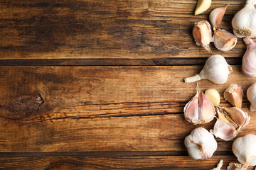 Fresh organic garlic on wooden table, flat lay. Space for text