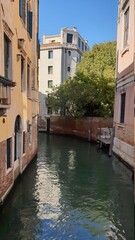 A small canal street in Venice. Old houses with Windows facing the canal. Italian flavor in Venice.