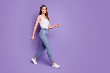 Full size profile side photo of happy cheerful woman go copyspace good mood walk isolated on purple color background
