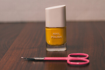 Yellow nail Polish and pink nail scissors. Hand care. Manicure and pedicure. The foreground is blurred. Space for text