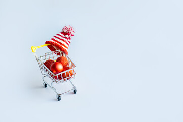 Red christmas balls in a shopping cart on a white background. New Year and Christmas shopping...