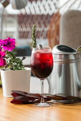 Cold refreshing drink with blueberries, black currants, juice, soda water and ice in wine glass on cafe table